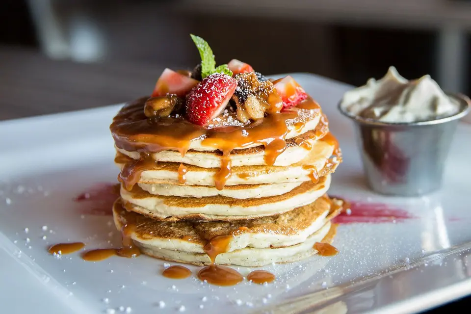 Stack of pancakes with strawberries, blueberries, and syrup